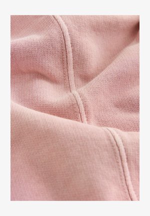 Svetloružová tkanina s jemnou rebrovanou textúrou, s viditeľným prešívaním a záhybmi, vystihujúca mäkkosť a poddajný pád.