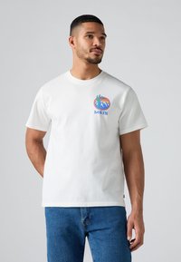 Witte katoenen T-shirt met korte mouwen en ronde hals, voorzien van een kleurrafische afbeelding van bergen en de tekst "LEV'S" op de borst.