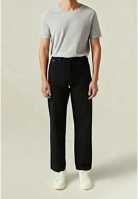 Camiseta gris de manga corta combinada con pantalones rectos negros y zapatillas blancas. El conjunto presenta un diseño simple y minimalista.