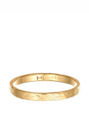 Anneau fin en or avec une texture martelée et des poinçons gravés sur la face intérieure, posé sur un fond blanc.