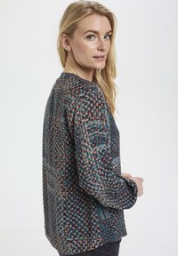 Camicia a maniche lunghe con motivo in blu, grigio e corallo, realizzata in tessuto testurizzato e con scollo rotondo. Presenta una vestibilità comoda e polsini con bottone.