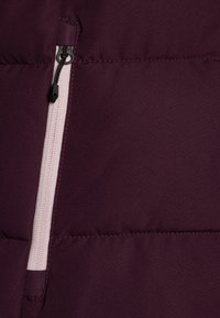 Bordo puffer jakna s vidljivim patentnim zatvaračem i kontrastnim svijetlo ružičastim oblogom. Ima kvadratni uzorak s quilted teksturom i šivanim šavovima.
