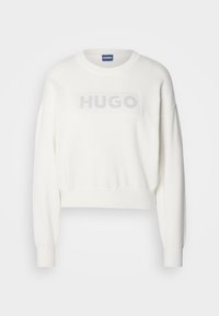 Pull blanc à manches longues et col rond, avec poignets et ourlet côtelés, présentant le texte "HUGO" en maille en relief subtile sur la poitrine.