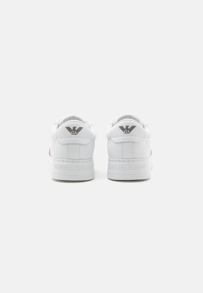 Paire de baskets blanches Emporio Armani vues de dos avec logo sur la languette du talon et nom de la marque embossé sur la semelle intermédiaire.