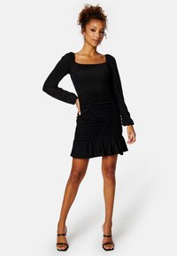 Czarna sukienka z długim rękawem, kwadratowym dekoltem, marszczonym ciałem i rozszerzanym dołem. Wykonana z teksturowanej tkaniny, z dopasowanym krojem.