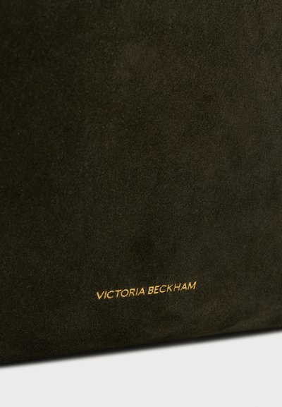 Geantă din piele suede verde închis, cu o textură netedă. Prezintă un logo auriu, embossat, care citește "VICTORIA BECKHAM" pe față.