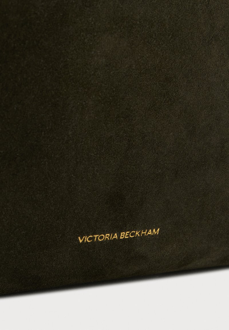 Sac à main en daim vert foncé avec une texture lisse. Il arbore un logo doré en relief portant l'inscription "VICTORIA BECKHAM" sur le devant.