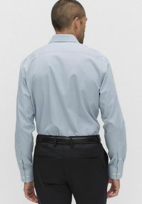 Lyseblåtternet skjorte med lange ærmer og klassisk krave, parret med sorte bukser. Har knapmanchetter og en knap-ned ryg.