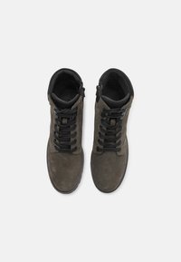 Baskets haute en suède gris foncé avec des lacets noirs, des accents en cuir et un col rembourré. Présente un design minimaliste et une surface texturée.