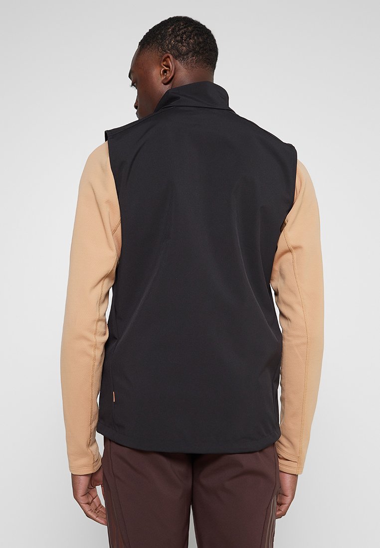 Schwarze ärmellose Weste mit hohem Kragen, die kontrastierende beige lange Ärmel hat, eine glatte Textur und minimalistische Designdetails aufweist.