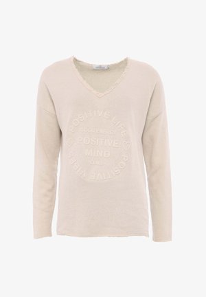 Beżowy sweter z długim rękawem w serek, wykonany z fakturowanej tkaniny, z wytłoczonym tekstem w okrągłym wzorze. Surowe wykończenie dekoltu.