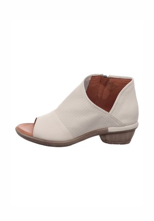 Beiger Damen-Lederstiefelette mit offenem Zehenbereich, perforiertem Obermaterial, seitlichem Reißverschluss, niedrigem Holzabsatz und beigem Innenfutter.