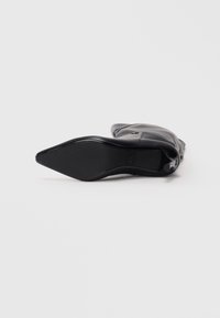 Zwarte hoge laars met een spitse neus en een gladde leren buitenkant. De zool is plat met een lichte curve aan de achterkant voor comfort.