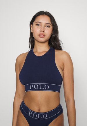 Marlmēlī krūšturis ar halter dekoltē, ar plašu joslu ar kontrastējošu "POLO" uzrakstu. Parādītas arī atbilstošas bikini apakšdaļas.