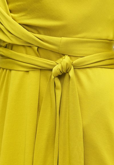 Rochie galbenă strălucitoare, cu accent la talie înnodată. Materialul are o textură netedă, cu un design simplu și o siluetă care avantajează.