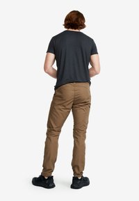 Bruna cargobyxor med slim fit och detaljer på bakfickorna, tillsammans med en mörkgrå kortärmad skjorta och svarta skor.