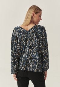 Langarmbluse mit einem abstrakten Muster in Blau, Schwarz und Creme, V-Ausschnitt hinten und weichem, strukturiertem Stoff.