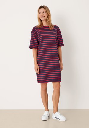 Robe en coton rayée présentant des rayures horizontales navies et roses, des manches courtes, une coupe décontractée et une longueur mi-genoux. Associée à des baskets blanches.