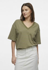 Camiseta de cuello en V de rayas verde oliva con corte holgado y mangas cortas; la tela parece suave con rayas horizontales blancas en toda la prenda.