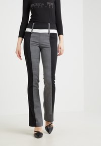 Zwart-grijs gemêleerde broek met een nauwsluitend ontwerp en een witte tailleband, met een houndstoothpatroon op de voorpanden.