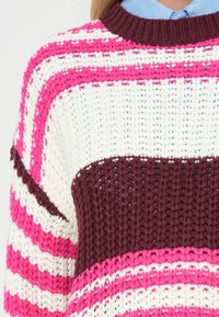 Camisola de malha com riscas geométricas em rosa, branco e bordô. Apresenta um decote canelado em bordô e uma trama solta e texturizada.