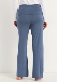 Siniset, leveälahkeiset housut, jotka on valmistettu pehmeästä ja kevyestä materiaalista. Ominaisuuksiin kuuluu paksu, taitettu vyötärö ja sileä pinta. Ei näkyviä kuvioita tai koristeita.