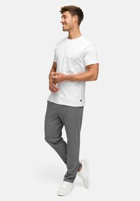 Hvit bomulls t-skjorte kombinert med grå joggebukser; modell som bærer hvite joggesko; avslappet passform, korte ermer, minimal detaljering.