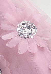 Tejido de tul rosa con aplicaciones de flores superpuestas. Las flores tienen pétalos translúcidos y un grupo central de brillantes lentejuelas plateadas.