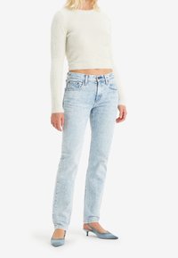 Ljusgrå croppad tröja med mjuk textur, kombinerad med ljusblå jeans med raka ben och klassisk femficksdesign samt blå klackar.