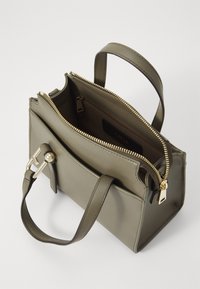 Sac à main en cuir vert olive avec un design structuré, fermeture éclair dorée, poche intérieure et une petite anse pour le porter.
