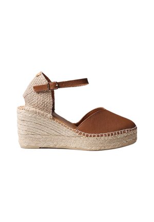 Espadrille à talon compensé marron avec talon tressé, bout fermé et bride ajustable à la cheville sur fond blanc.