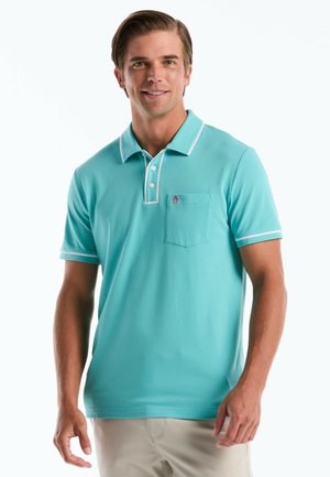 Mann trägt türkisfarbenes Kurzarm-Poloshirt mit weißem Besatz und Taschenemblem, steht vor weißem Hintergrund.