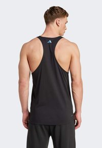 Débardeur de sport noir avec dos nageur, fabriqué en tissu lisse. Présente un logo Adidas bleu près du cou et une coupe ajustée.