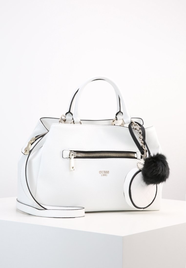 Biała syntetyczna torba na ramię z czarnymi akcentami, wyposażona w przednią kieszeń na zamek, podwójne uchwyty oraz odpinany brelok w kształcie pompona.