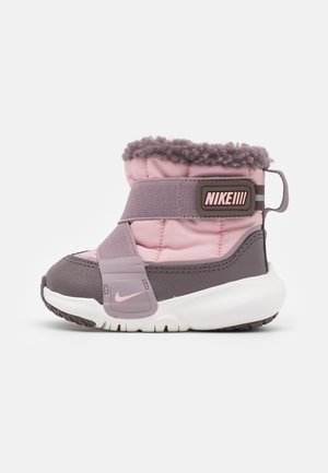 Pink og grå børnestøvle med fluffy krave, elastisk rem, hvid sål og Nike-logo på siden og remmen, vist på hvid baggrund.