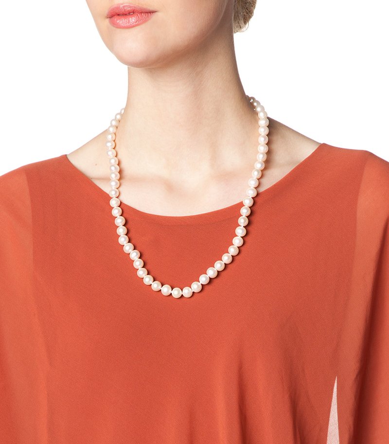 Pearl necklace with round, white pearls on a model, worn over an orange top. The necklace features a uniform size and smooth texture.