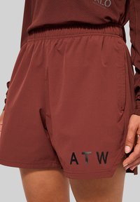 Tamsiai raudoni šortai su elastinga juostele, turintys dvi šonines kišenes ir juodai spausdintą "ATW" ant apatinės kairės kojos.