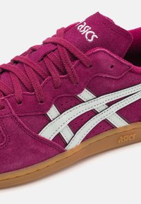 Zapatillas de ante moradas con franjas sintéticas blancas, suela de goma ycordones a juego. Presenta detalles cosidos y un logotipo en la lengüeta.