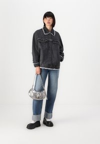 Must värvitud denimmantel, franjeerimisega servad, kaks rinna-taskut, kombineeritud siniste voltidega teksade ja hõbedase kotiga. Raskesti mustad platvormijalatsid.