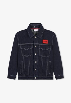 Donkerblauwe spijkerjack met witte stiksels. Beschikt over een rood logo-oprits, twee borstzakken en metalen drukknoopsluitingen.