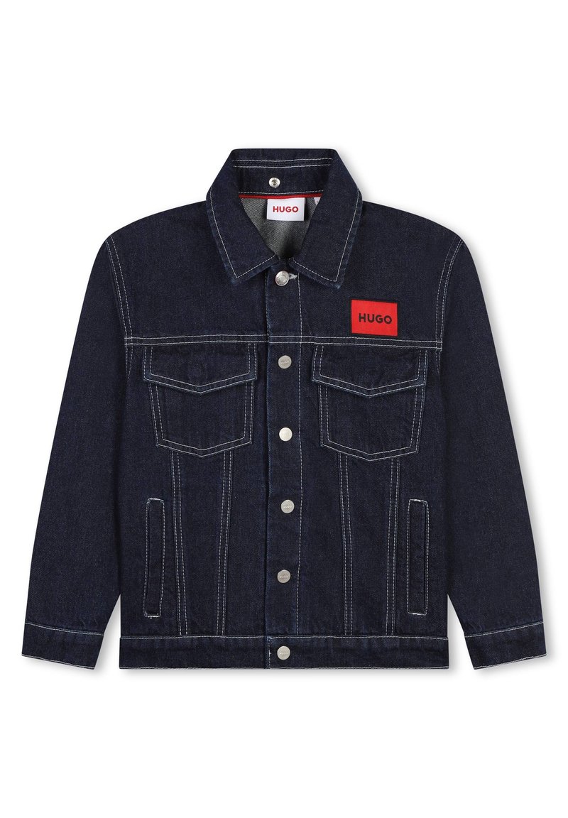 Denim jakna v temno modri barvi z belim šivanjem. Ima rdečo logotipno nalepko, dva žepa na prsih in kovinske gumbke na pritisek.