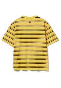 Žluté tričko s vodorovnými hnědými pruhy, krátkými rukávy a kulatým výstřihem. Na zádech má malý detail s logem.