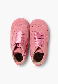 Bottes chelsea en suédine rose avec des perforations décoratives, des lacets en satin et des fermetures éclaires sur les côtés pour un enfilage facile. Doublure intérieure douce visible.
