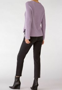 Lilac knitted sweater with a round neck, paired with black slim-fit jeans and black heeled ankle boots, showcasing a fitted silhouette.
