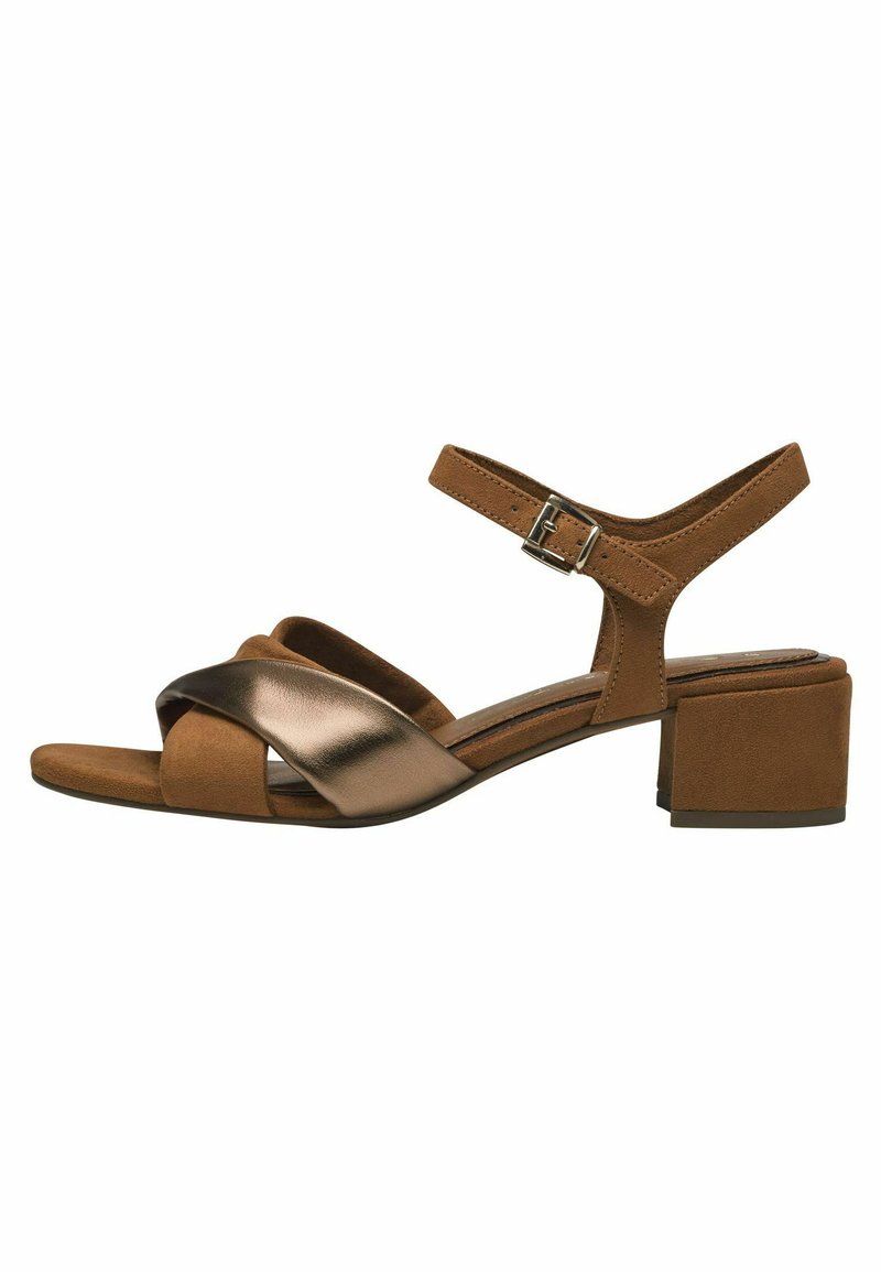 Brown suede block-heel sandal featuring crossed metallic straps, adjustable ankle buckle, and a textured insole for comfort.