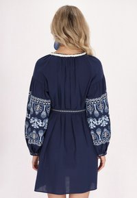 Marineblaues Kleid mit gestickten blauen Blumenmustern an den langen Ärmeln, einem runden Ausschnitt und einer taillierten Silhouette mit einem dekorativen Gürtel.