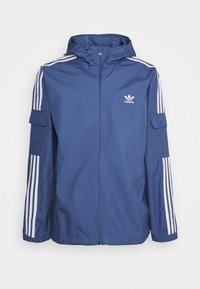 Mörkblå zip-uppjacka i lätt material, med tre vita ränder på varje ärm och en liten logotyp på bröstet.