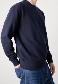 Námořnicky modrá mikina s kulatým výstřihem vyrobená z měkké bavlny, s žebrovanými manžetami a lemem, s volnějším střihem a jednoduchým designem.