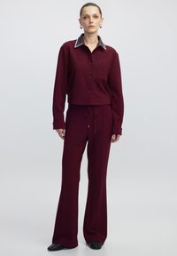 Bordeaux twee-delige set met een cropped button-up shirt met een grijze kraag, rechte pijpen en een gestructureerde stof.