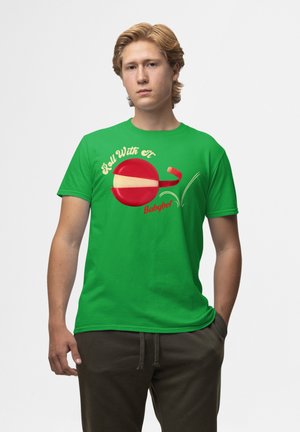 Grøn bomulds T-shirt med et rødt og gult cirkulært grafisk design, der har teksten "Roll With It" og "Babybel" logoet i legende skrifttype.